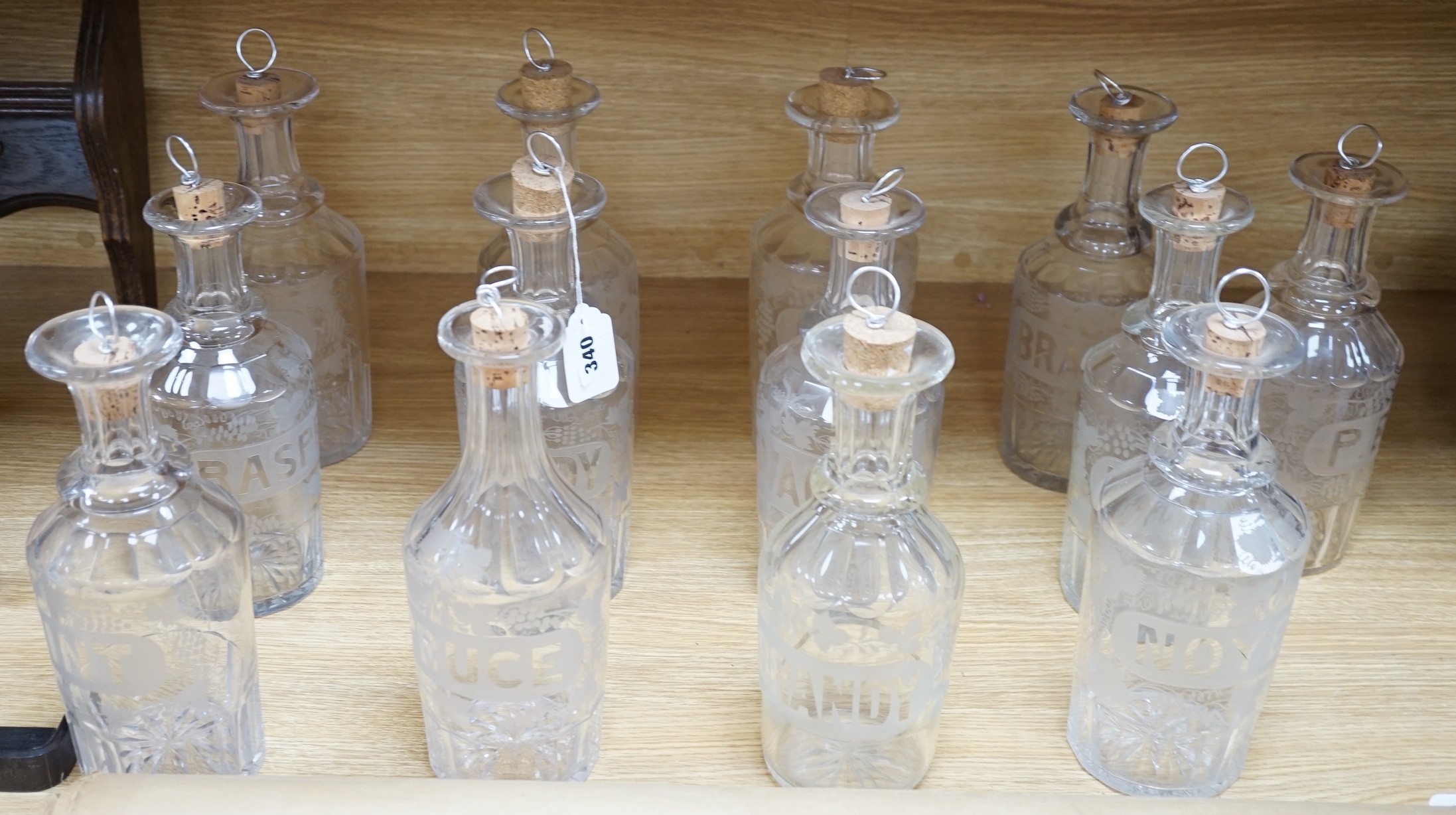 A set of 13 Victorian etched and named glass decanters; 27 cm.